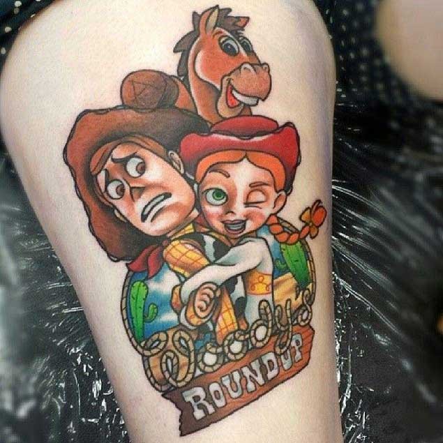 Nice cartoon like colored funny heroes tattoo on thigh with lettering