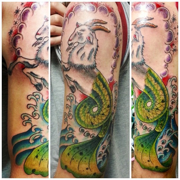 Tatuaje en el brazo,
capricornio blanco fascinante con la cola verde