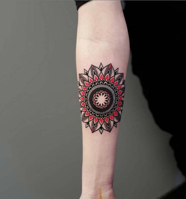 Nice colored little ornamental flower tattoo on forearm