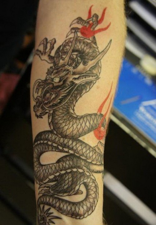 Nice gray-ink dragon with red ribbons tattoo on forearm