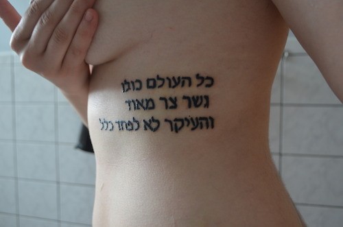 Tatuaje de texto hebreo en las costillas