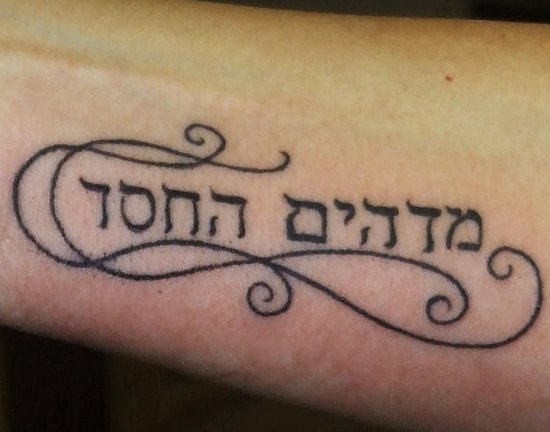 Tatuaje  de frase hebrea con rizos