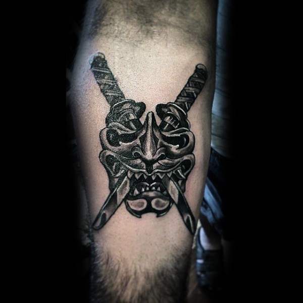 Nice looking black ink samurai mask tattoo on forearm with crossed swords