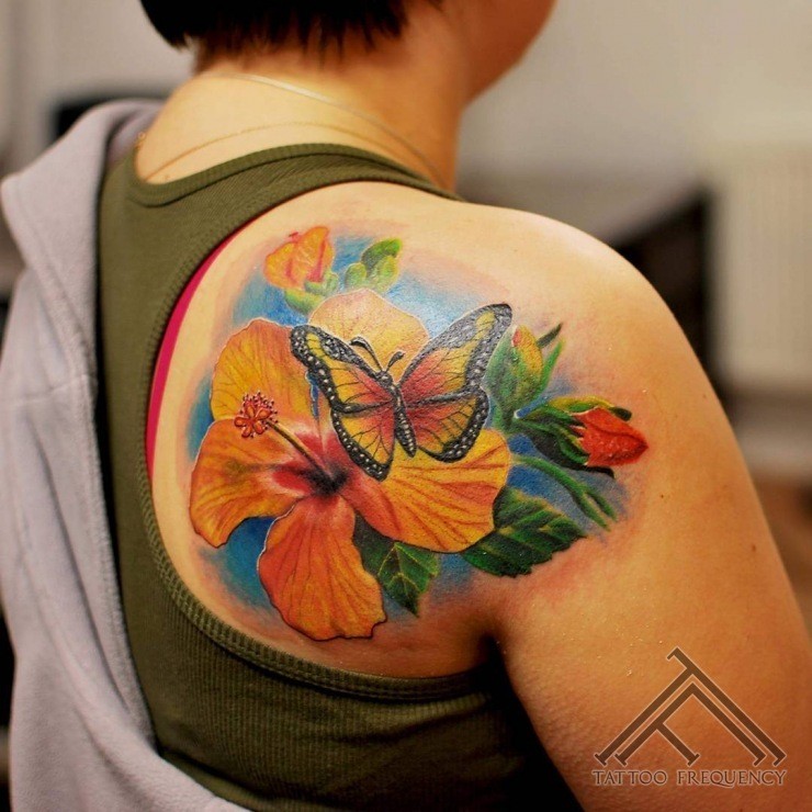 Nice looking colored scapular tattoo of beautiful lily with butterfly