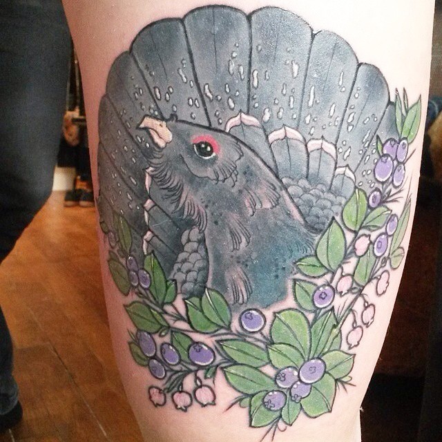 Nice looking colored thigh tattoo of bird and berries