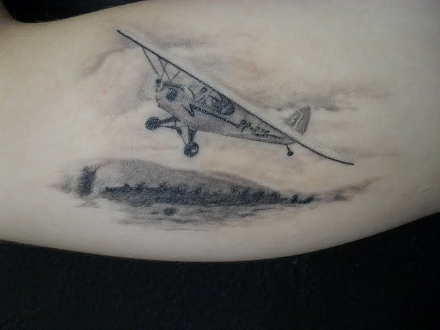 Nice looking detailed biceps tattoo of little plane