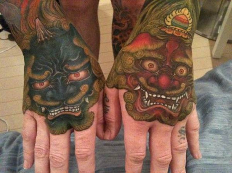 Nice looking multicolored on hands tattoo of various Asian demons