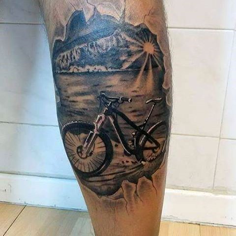 Tatuaje en la pierna, bicicleta de montaña en la orilla del lago