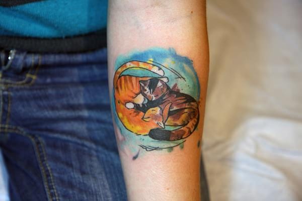Old Asian cartoon style colored forearm tattoo of cat couple