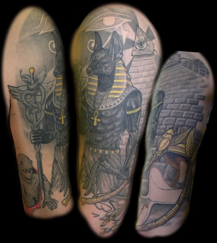 Old cartoon like colored detailed Anubis God tattoo on shoulder with pyramids