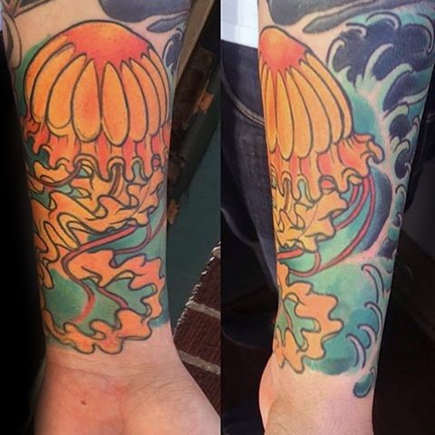 Old cartoon like colored jellyfish in waves tattoo on wrist