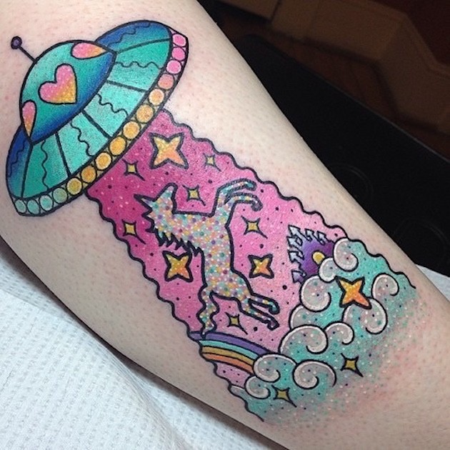 Old cartoon like colored leg tattoo with alien ship and unicorn with stars