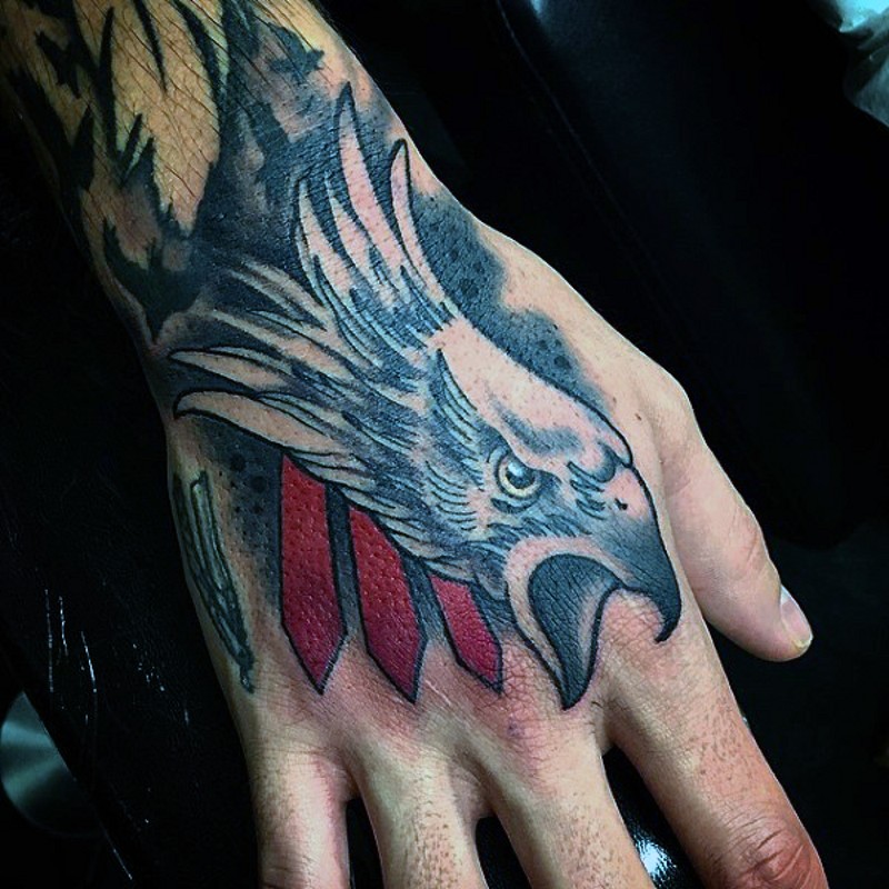 Old cartoon style colored eagle head tattoo on hand with red stripes