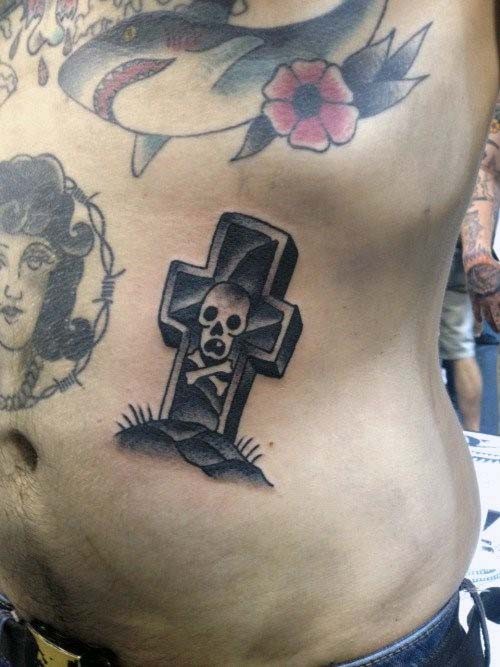 Tatuaje en el costado, cruz de piedra con calavera