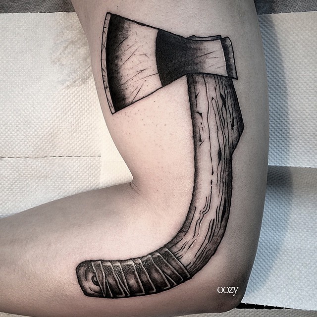 Old cracked wooden ax with cracks curved tattoo on arm