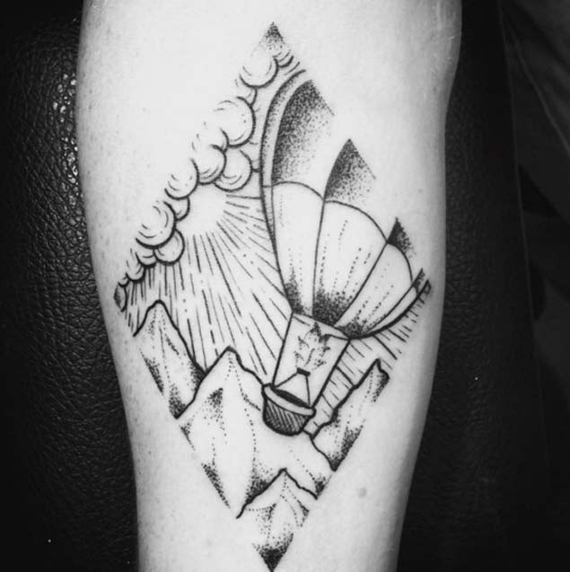Tatuaje en el brazo, globo aerostático entre montañas, dibujo viejo