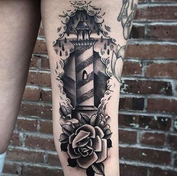 Old school black ink lighthouse tattoo on thigh with big rose