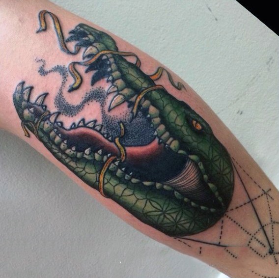 Old school colored alligator head with ribbon tattoo on leg
