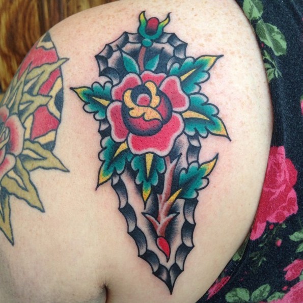 Old school colored antic weapon tattoo on shoulder stylized with massive flower and leaves
