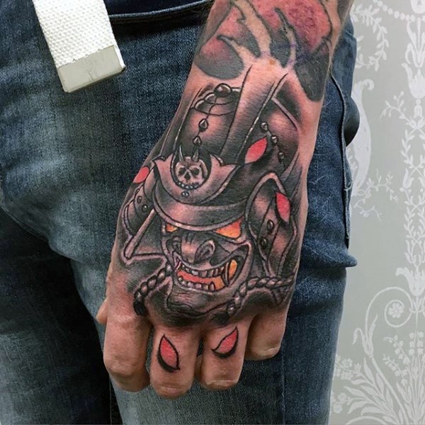 Old school colored demonic samurai mask tattoo on hand with leaves