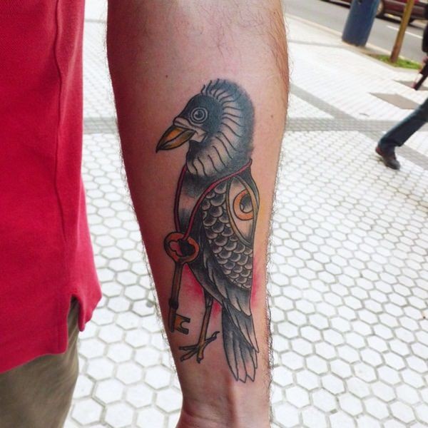 Old school colored little bird with key tattoo on forearm stylized with mystical eye