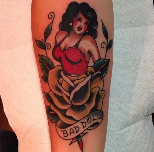 Old school colored little seductive woman tattoo on forearm combined with rose flower and lettering