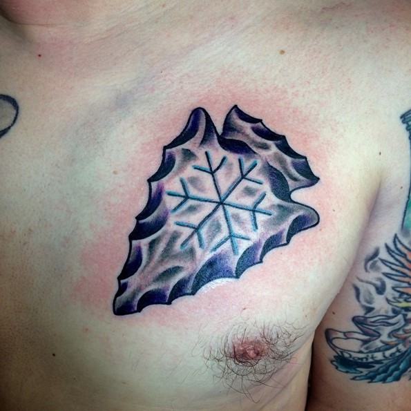 Old school designed colored ancient arrow head tattoo on chest stylized with snowdrop