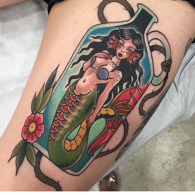 Old school interesting looking colored mermaid in bottle tattoo stylized with flowers
