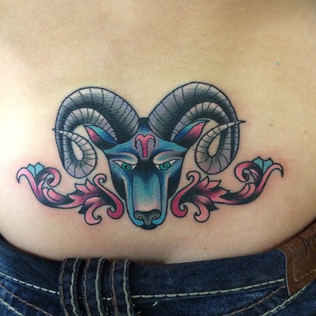 Tatuaje en la espalda baja, 
aries multicolor con signo en la frente