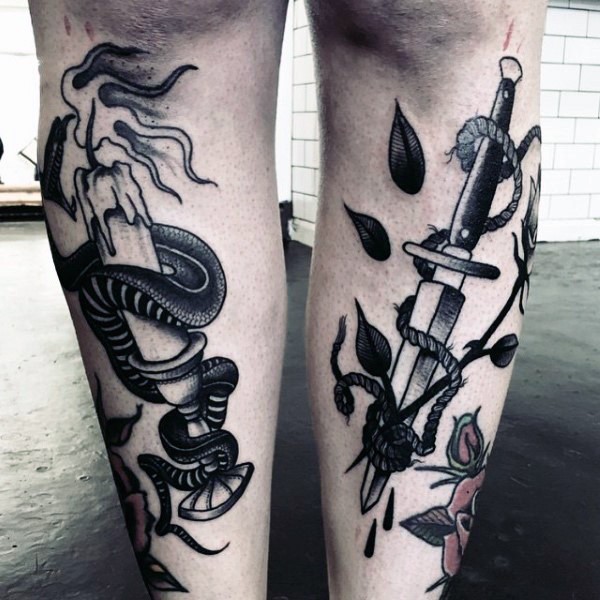 Old school style black and white legs tattoo of dagger with snake and candle