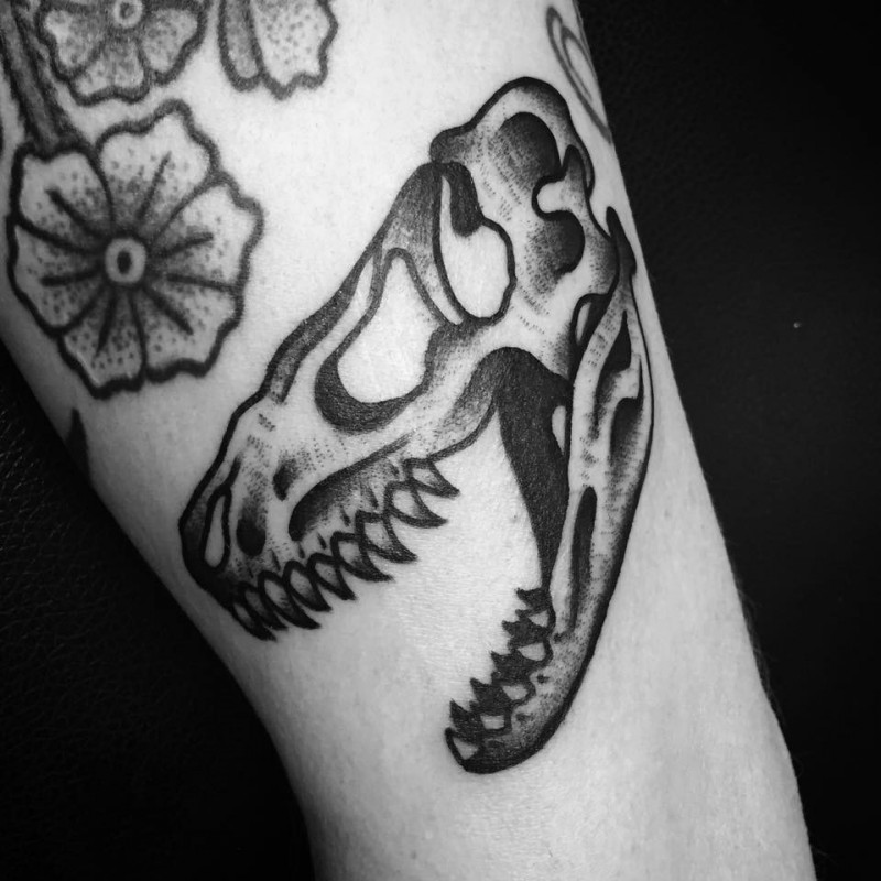 Old school style black ink arm tattoo of dinosaur skull