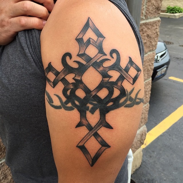 Tatuaggio a forma di croce in inchiostro nero stile vecchia scuola sul braccio