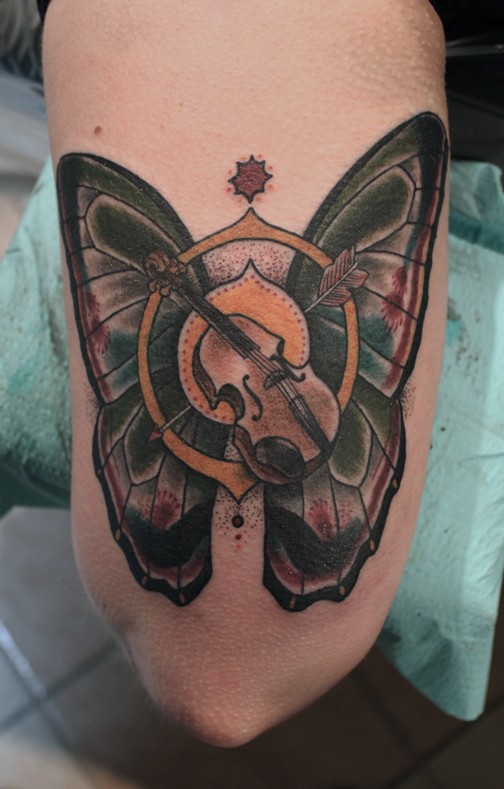 Old school style colored arm tattoo of butterfly with arrow and violin