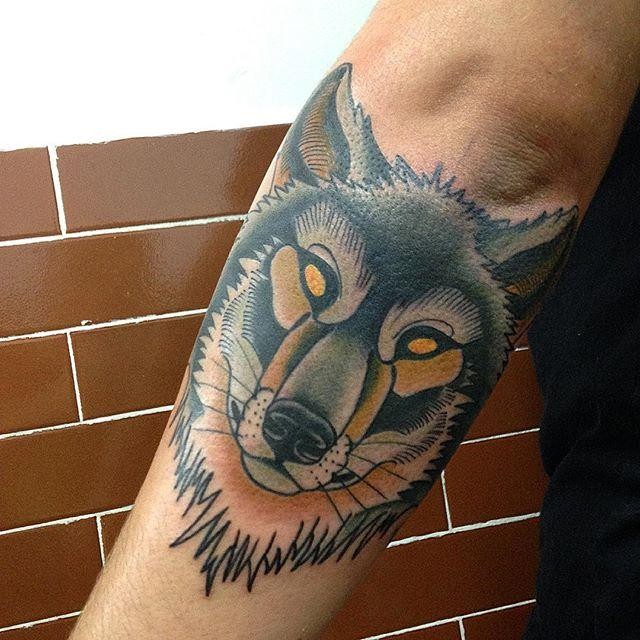 Old school style colored arm tattoo of wolf with yellow eyes