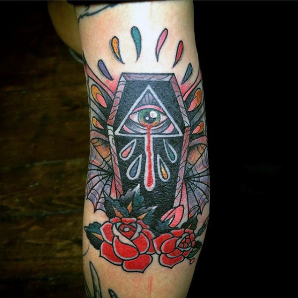 Tatuaje en el brazo, ataúd con ojo y gotas de sangre entre flores, estilo old school