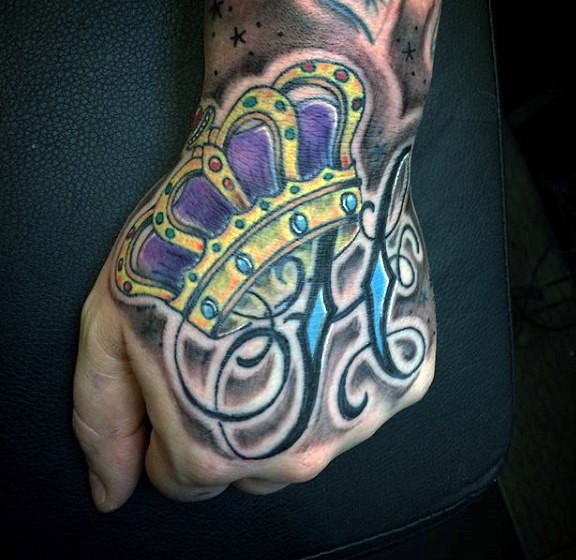 Old school style colored crown tattoo on hand with lettering
