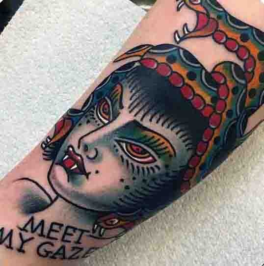 Oldschool gefärbte böse Meduse mit Schriftzug Tattoo am Arm