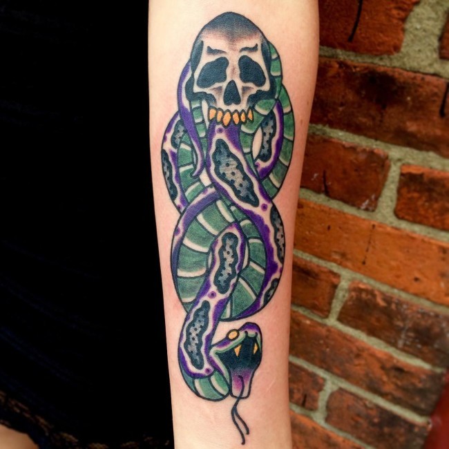 Old school style colored forearm tattoo of snake with skull