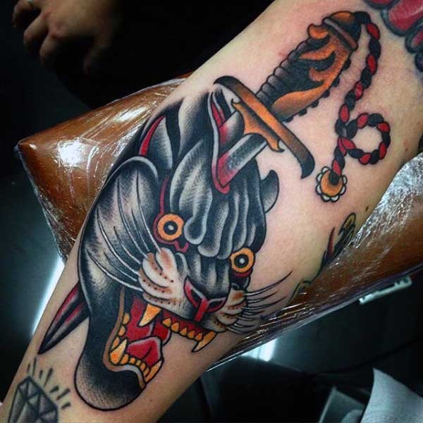 Old school style colored forearm tattoo of black panther with bloody dagger
