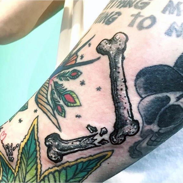 Oldschool Stil farbiges Unterarm Tattoo mit gebrochenen menschlichen Knochen