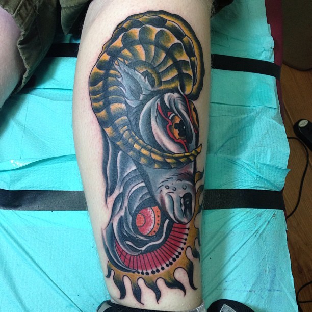 Old school style colored goat head tattoo on leg with tribal sun