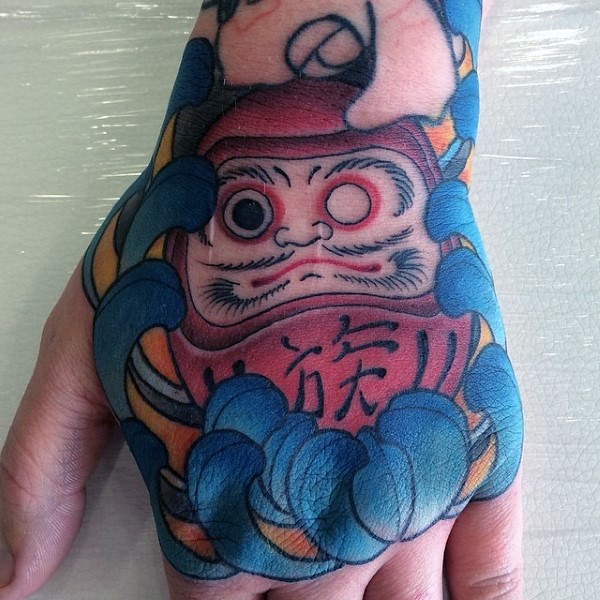 Old school style colored hand tattoo of daruma doll with flower
