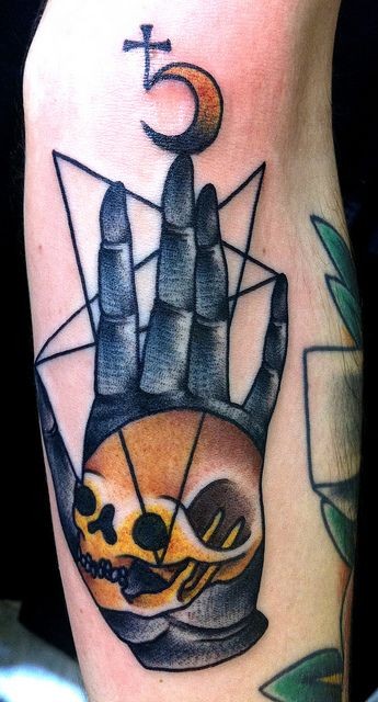 Old school style colored human skull with black hand tattoo