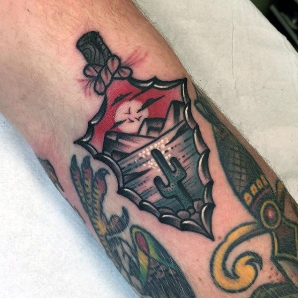 Old school style colored leg tattoo of arrowhead with desert picture