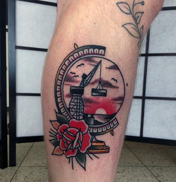 Old school style colored leg tattoo of globe with rose stylized with crane