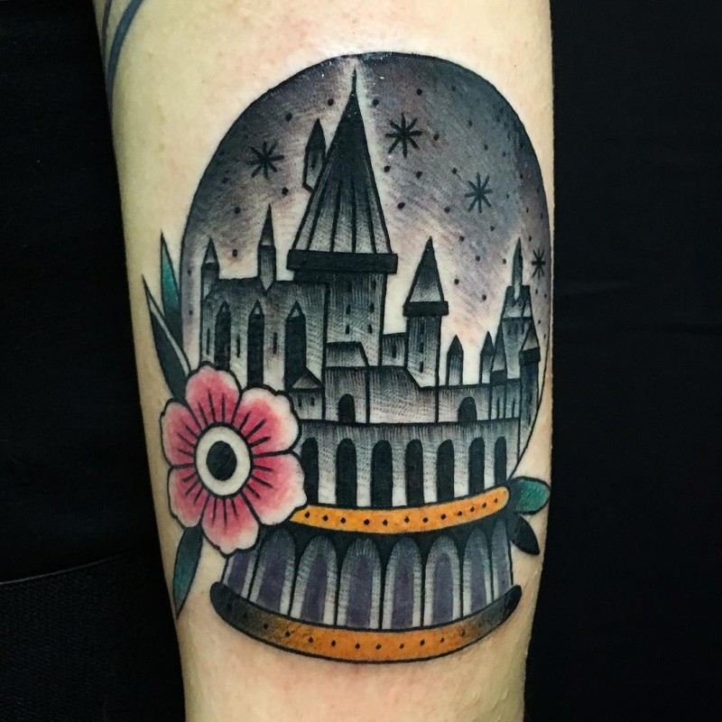 Old school style colored magical orb tattoo on forearm stylized with magical castle and flower