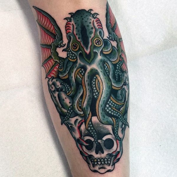 Old school style colored mystical octopus with bat wings tattoo on leg combined with human skull