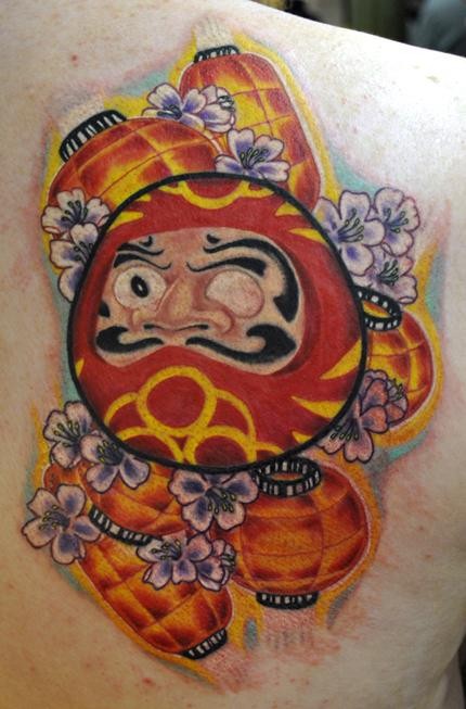 Old school style colored scapular tattoo of daruma doll with lights and flowers