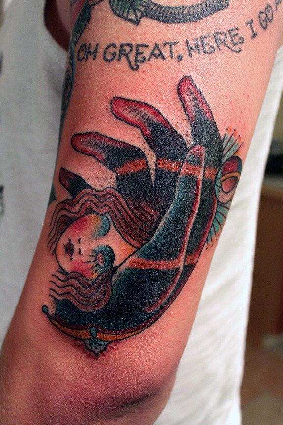 Old school style colored shoulder tattoo of hand hold dolls head