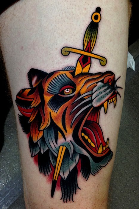 Old school style colored thigh tattoo of lion head with dagger